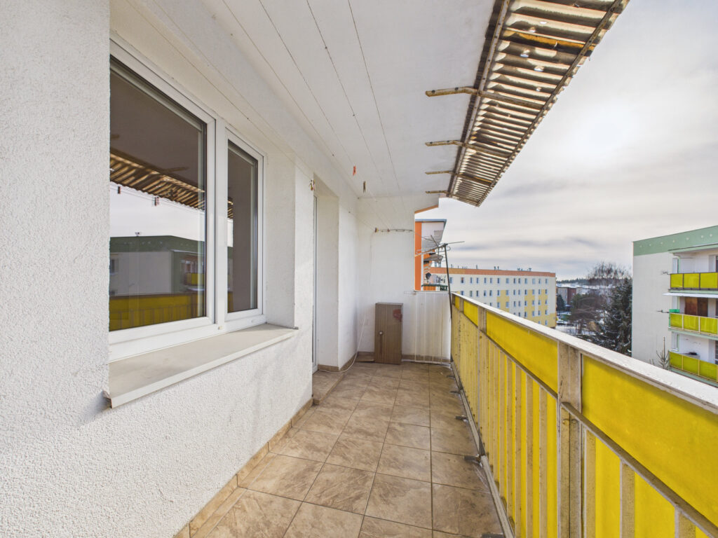 Balkon z żółtą balustradą i widokiem na bloki