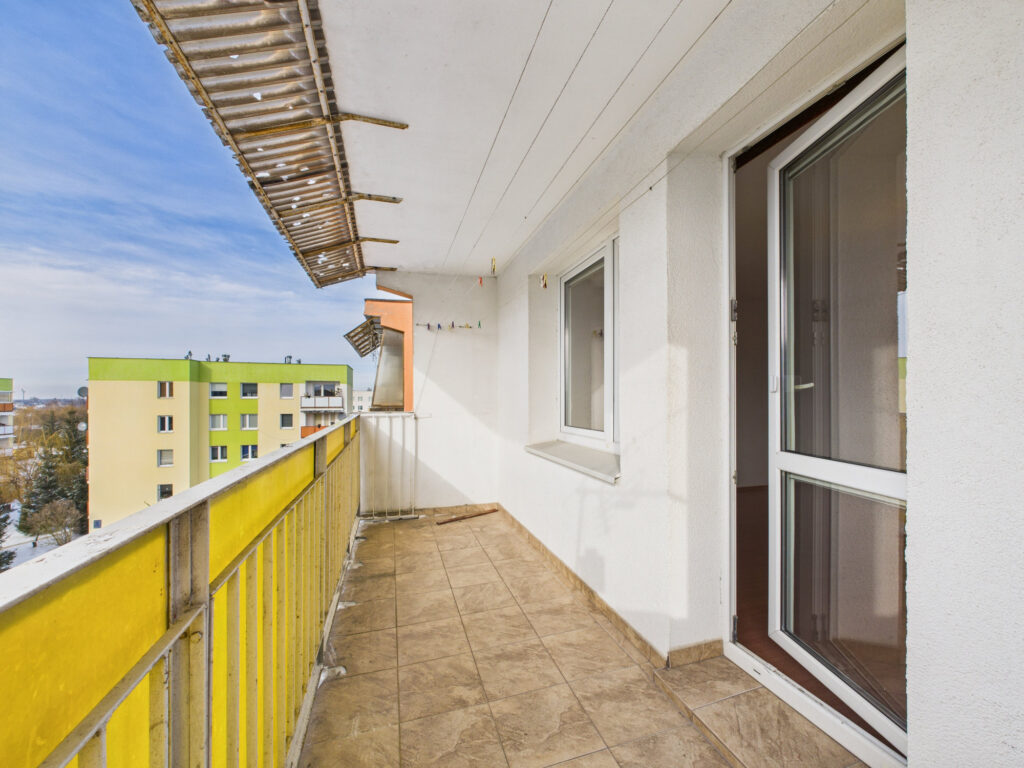 Balkon z widokiem na bloki mieszkalne.