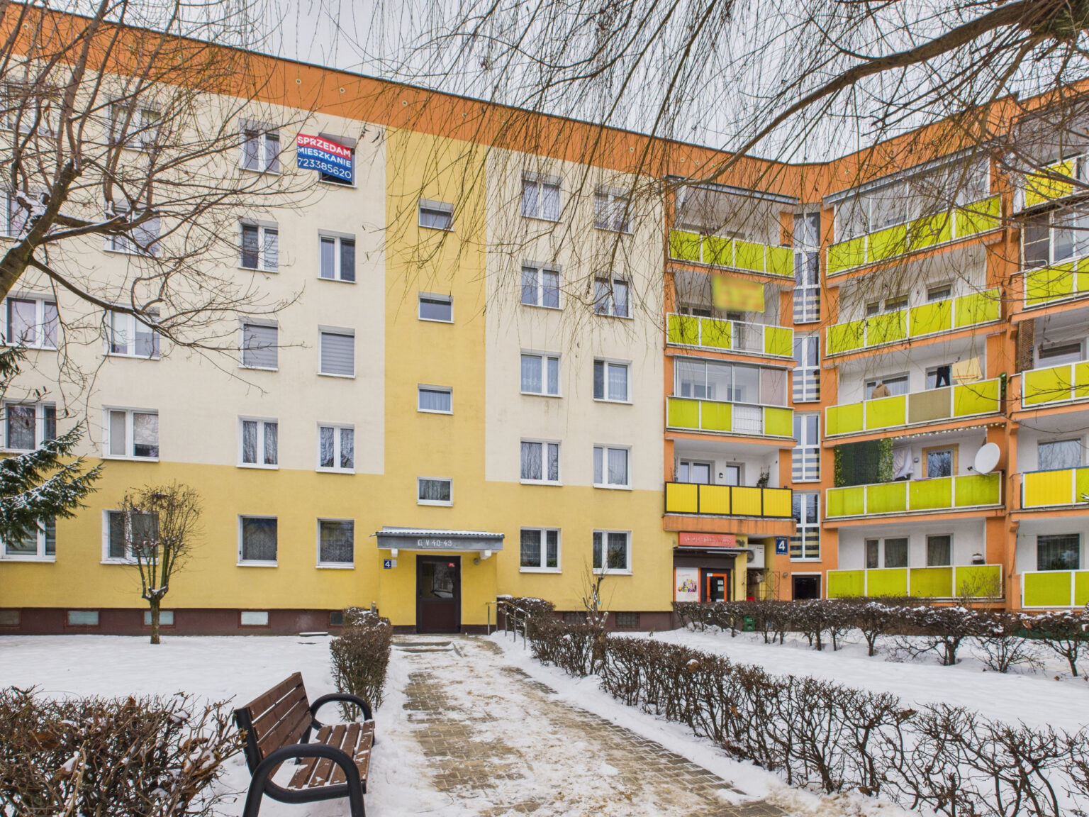 Blok mieszkalny z żółtymi balkonami zimą
