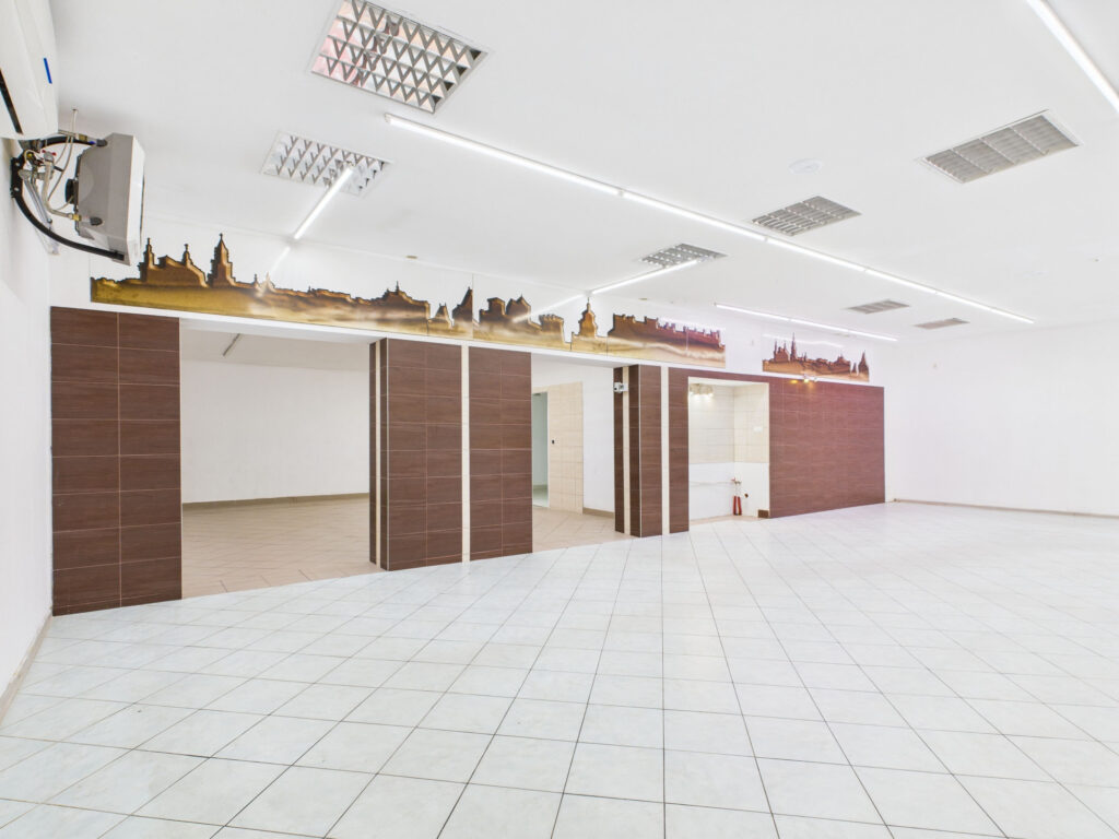 Puste wnętrze lokalu użytkowego z muralem panoramy miasta