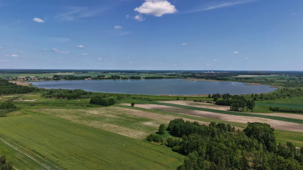 Jezioro otoczone polami i lasami z lotu ptaka