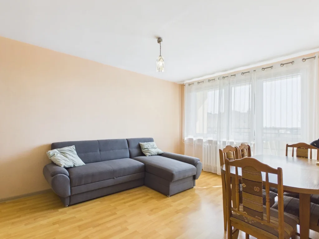 Jasny salon z szarą sofą i stołem