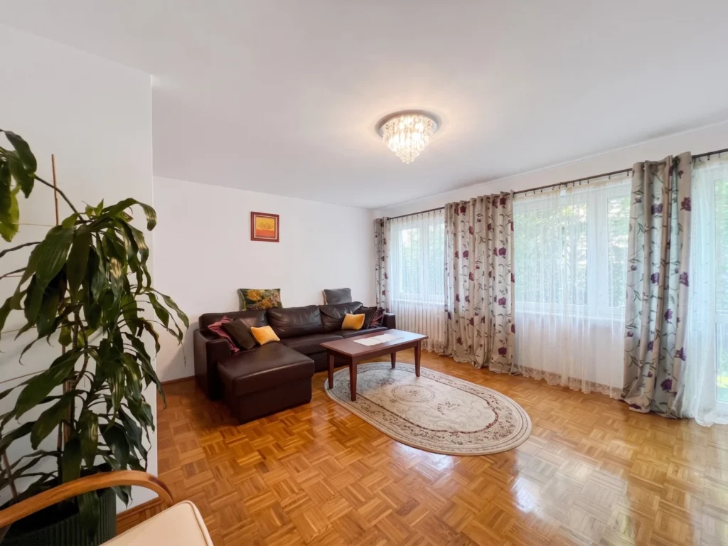 Jasny salon z brązową sofą i dużymi oknami