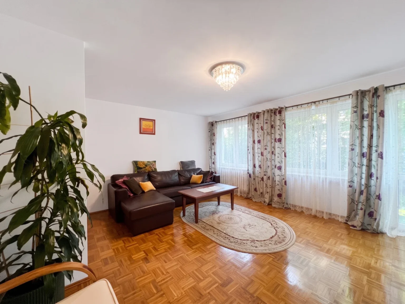 Jasny salon z brązową sofą i dużymi oknami