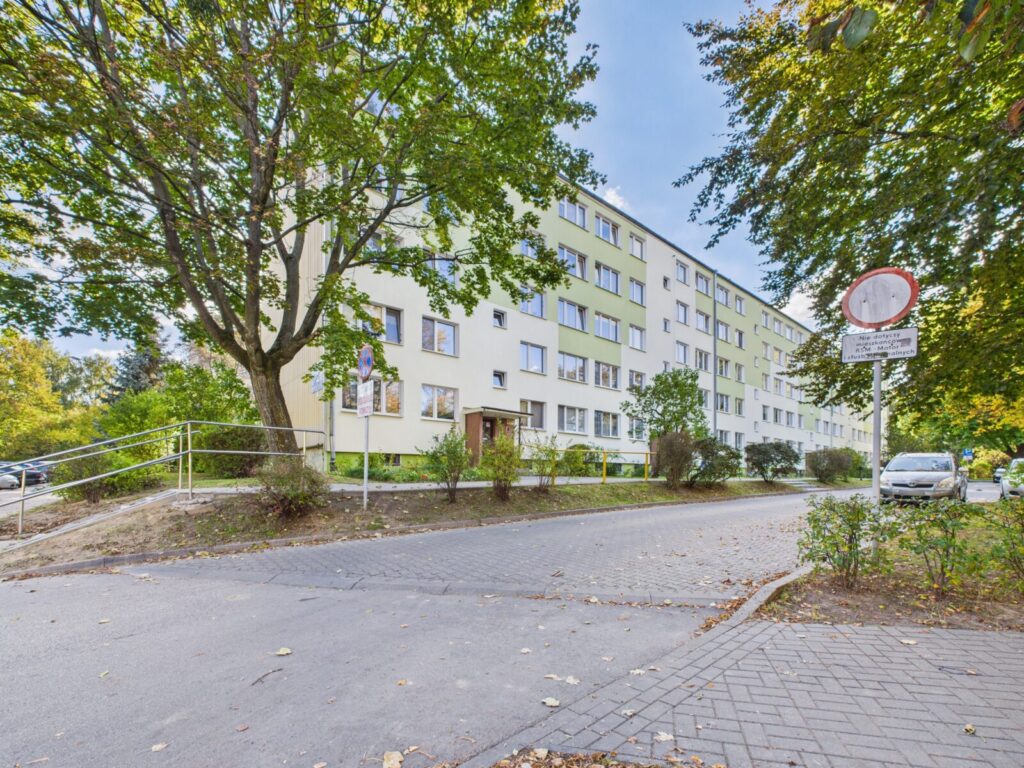 Czteropiętrowy blok mieszkalny wśród drzew