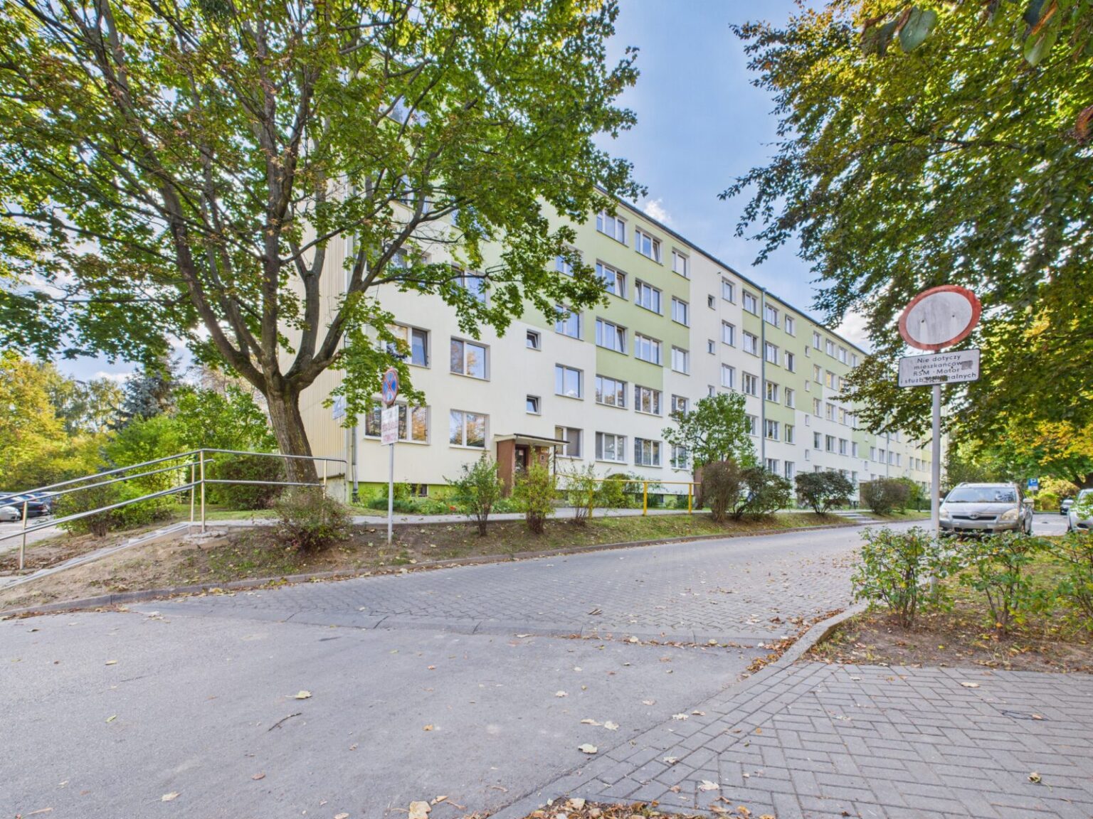 Czteropiętrowy blok mieszkalny wśród drzew