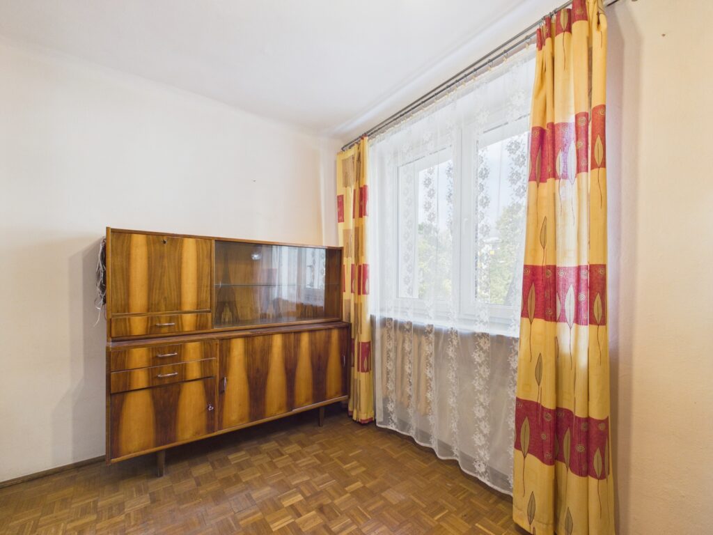 Pusty pokój z drewnianym kredensem i dużym oknem