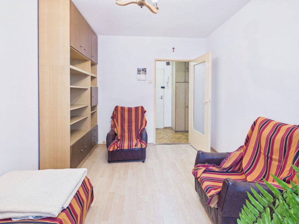 Jasny salon z fotelami, zabudową i otwartymi drzwiami
