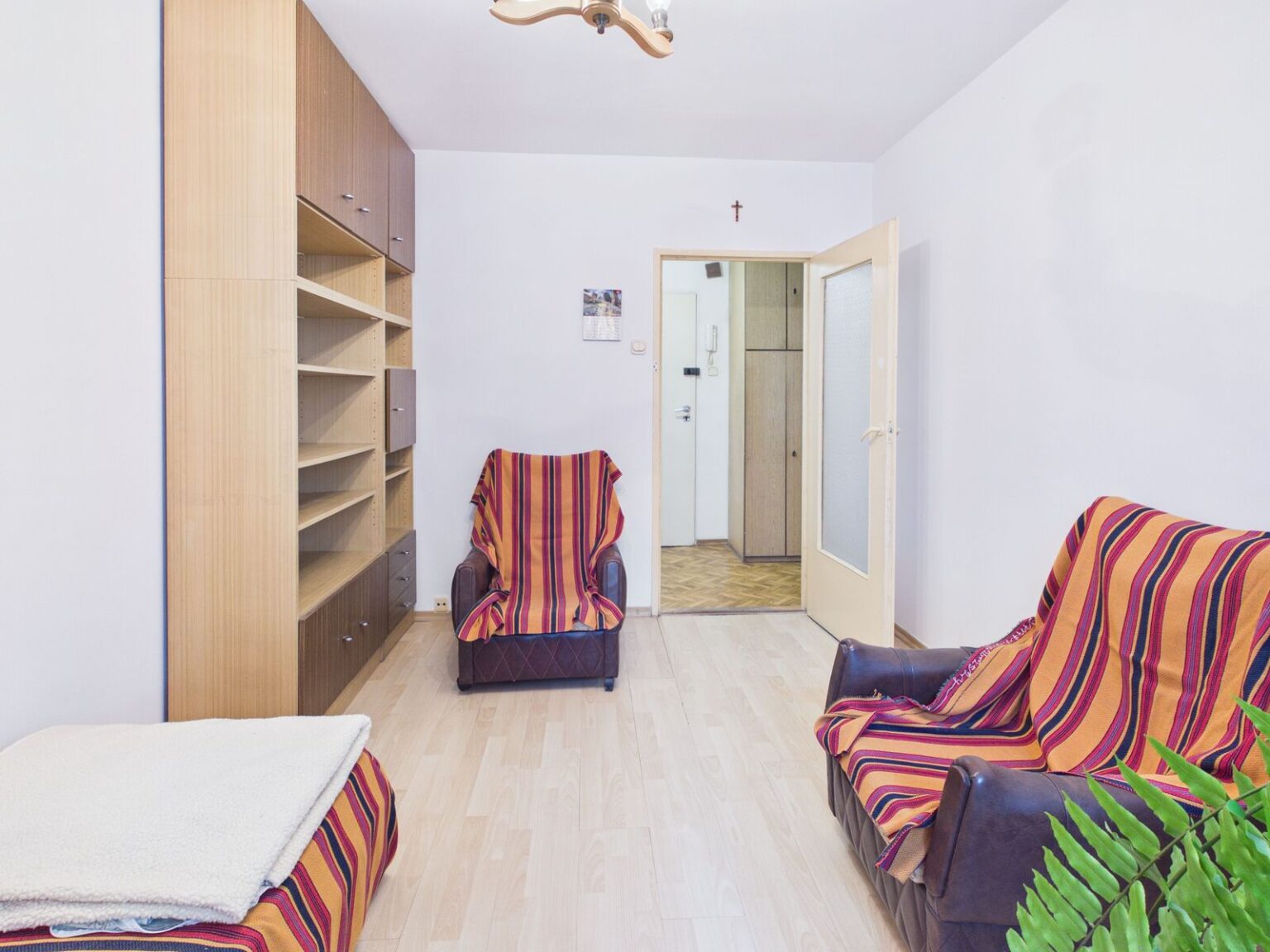 Jasny salon z fotelami, zabudową i otwartymi drzwiami