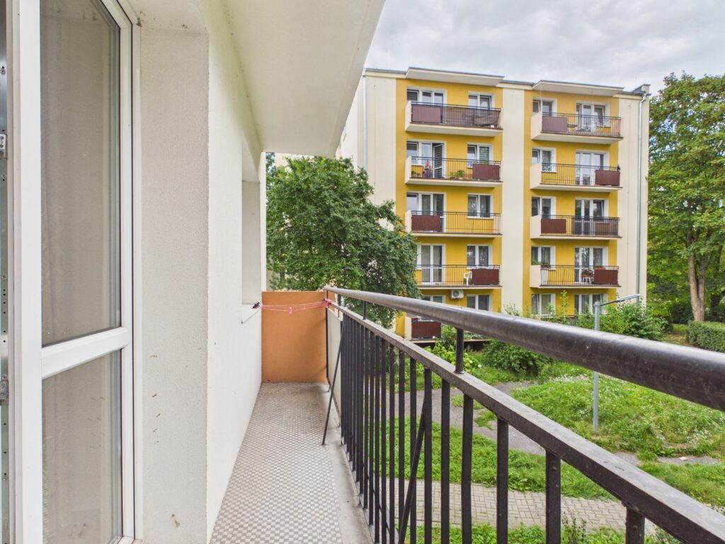 Balkon z widokiem na żółty blok mieszkalny