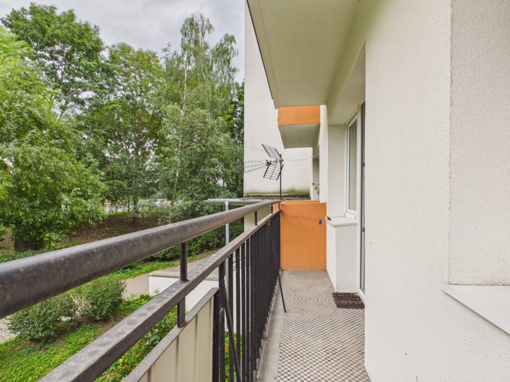 Wąski balkon z widokiem na zielone drzewa