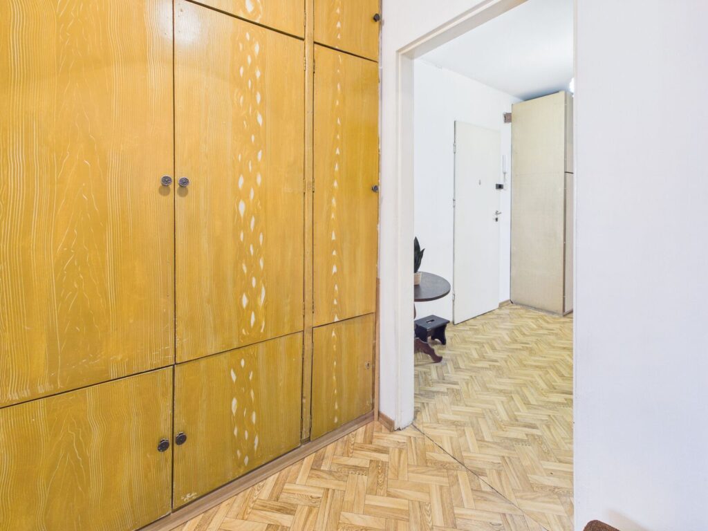 Drewniana zabudowa w jasnym przedpokoju z parkietem