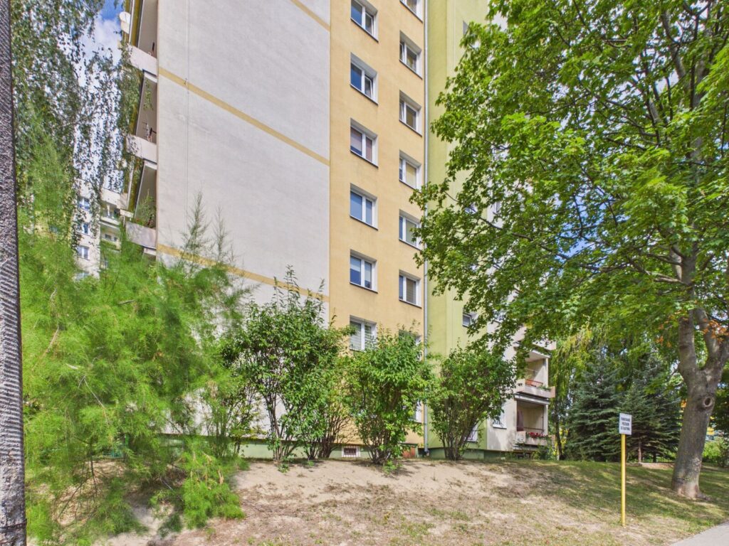 Kolorowy blok mieszkalny otoczony drzewami i krzewami