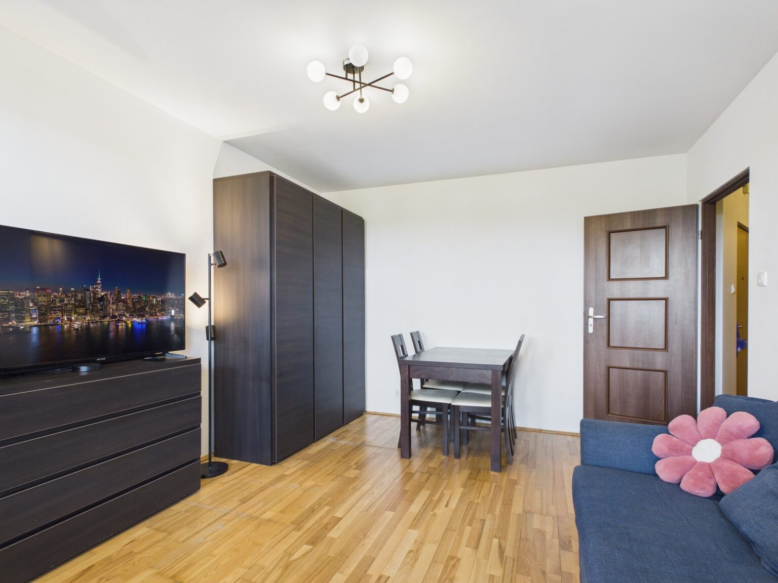 Jasny salon z jadalnią, ciemnymi meblami i sofą