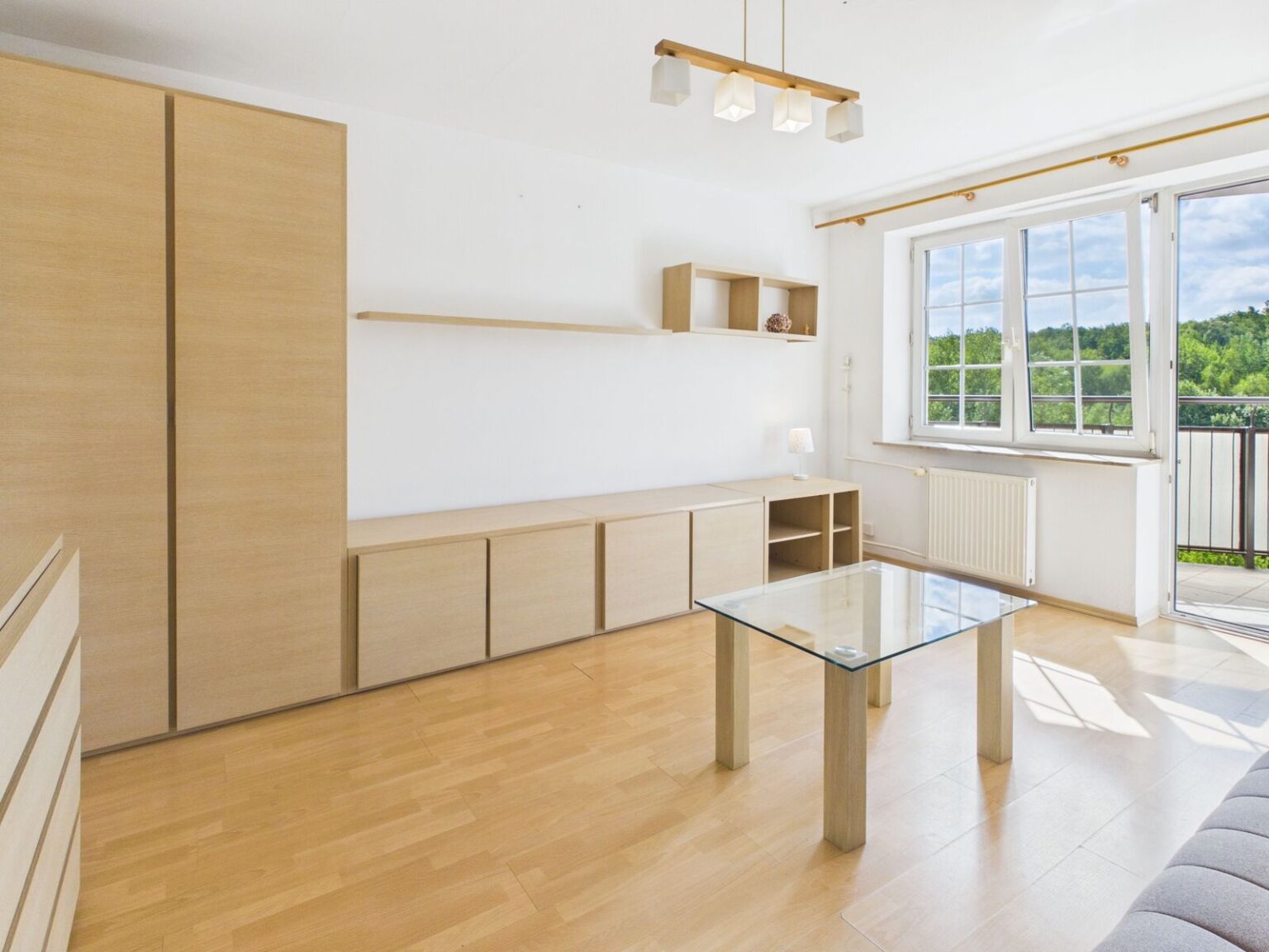 Jasny salon z drewnianą zabudową i balkonem