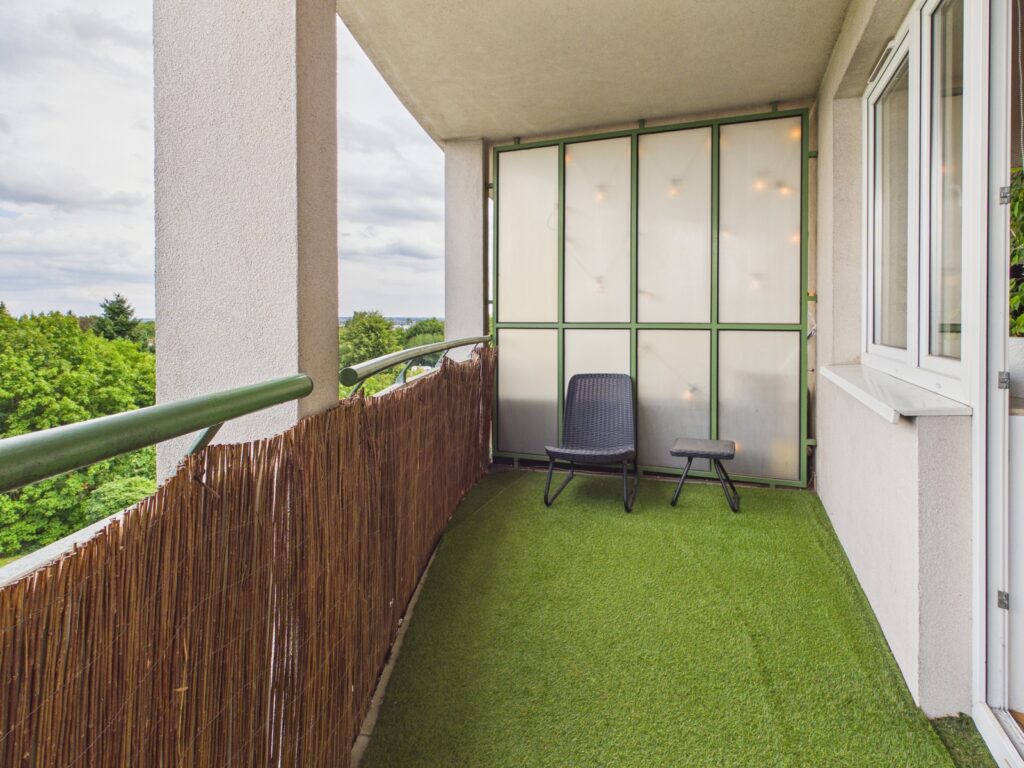 Balkon z fotelem, stolikiem i widokiem na drzewa
