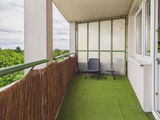 Balkon z fotelem, stolikiem i widokiem na drzewa