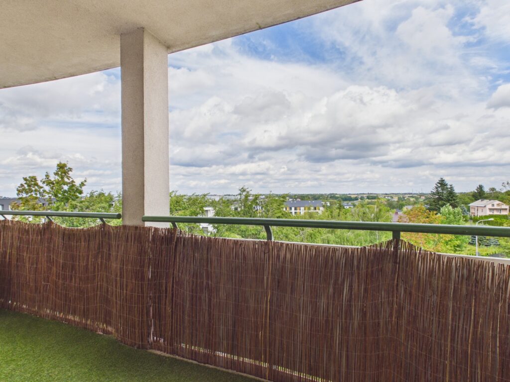 Zadaszony balkon z widokiem na zieloną okolicę