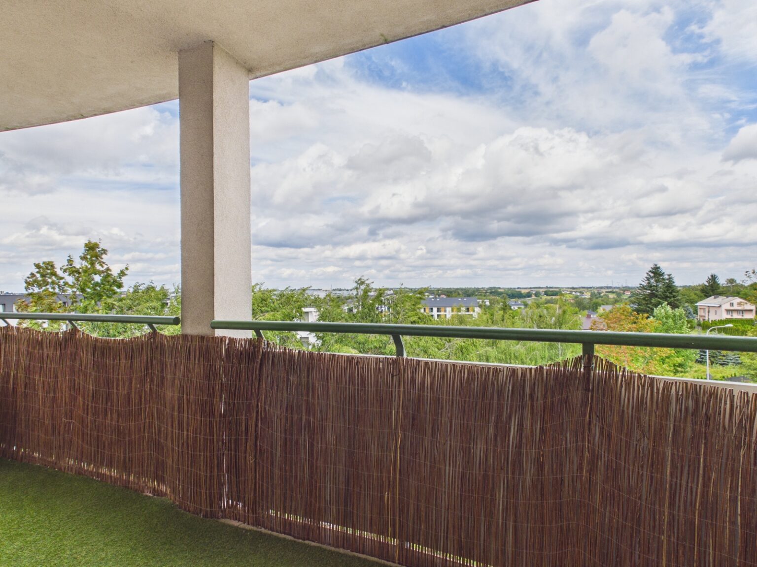 Zadaszony balkon z widokiem na zieloną okolicę