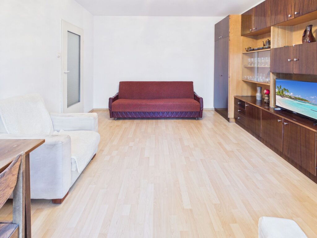 Jasny salon z bordową sofą i meblościanką