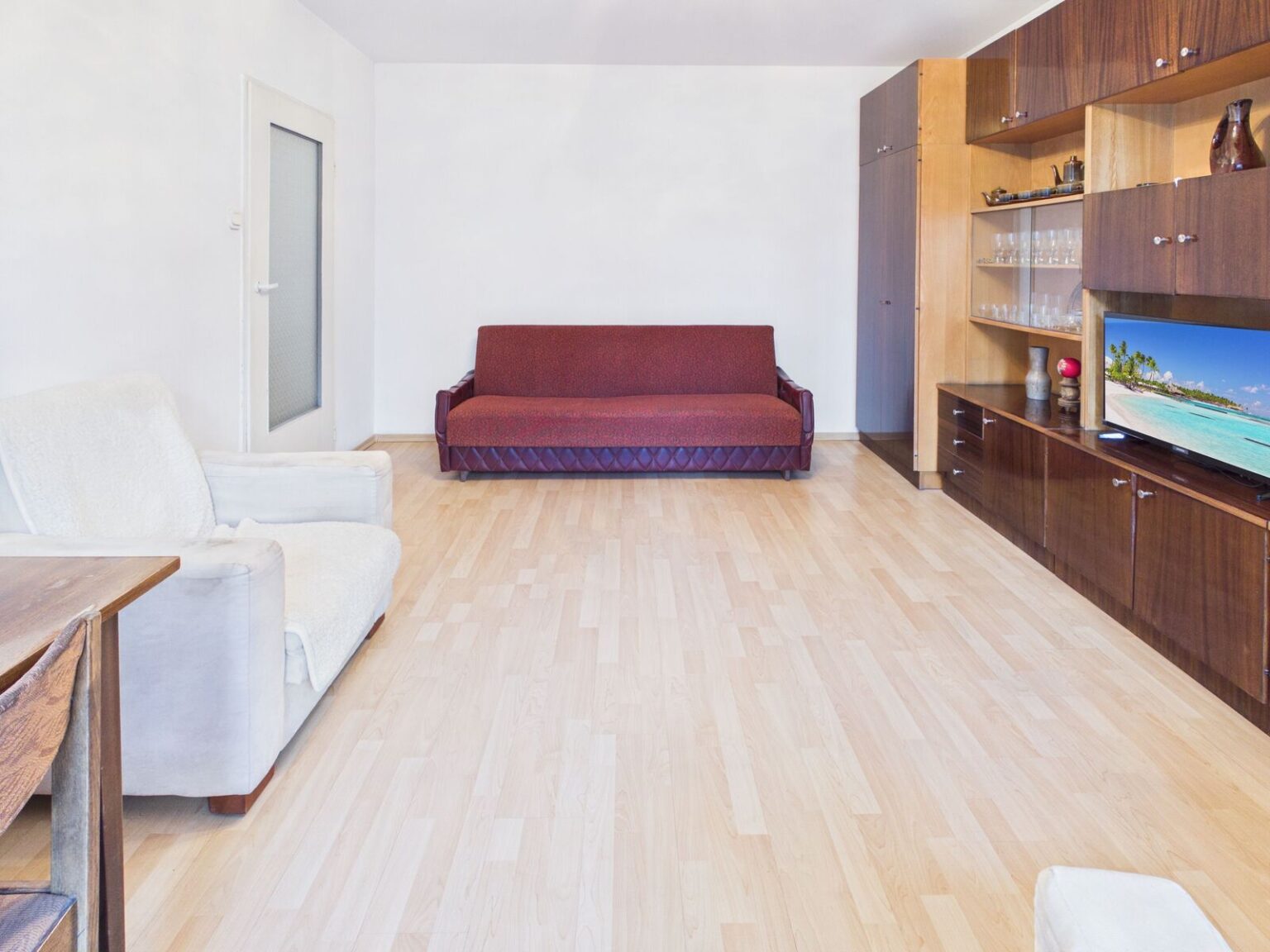 Jasny salon z bordową sofą i meblościanką