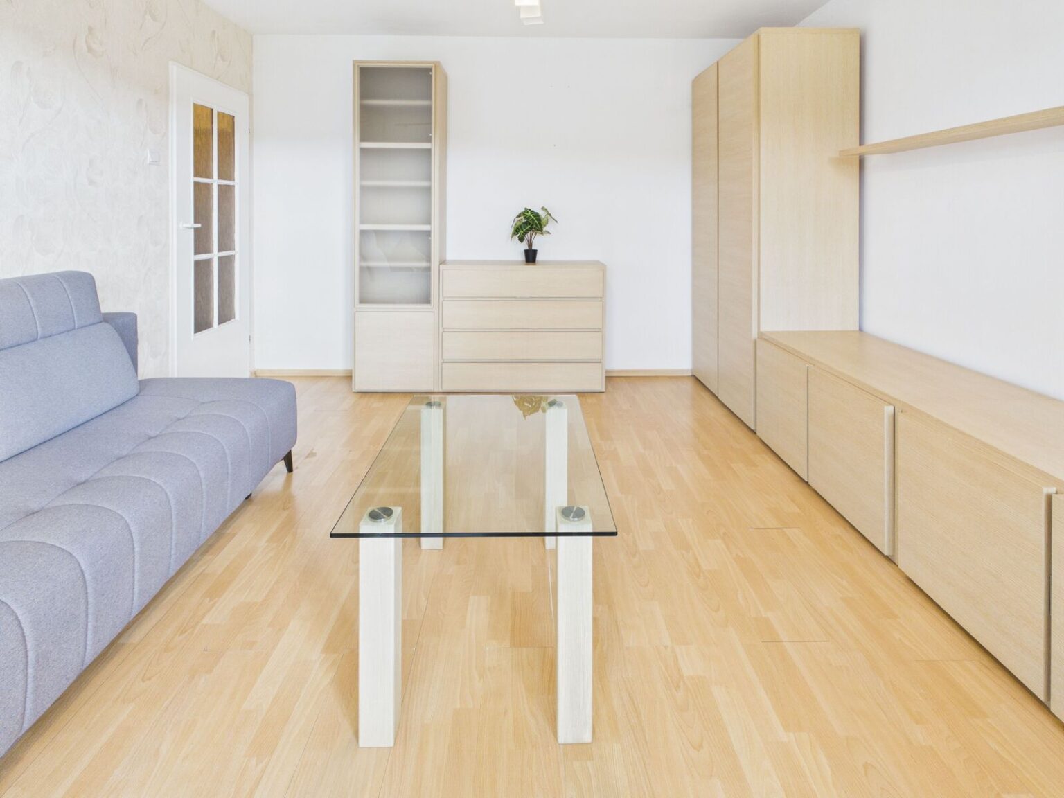 Jasny salon z szarą sofą i drewnianymi meblami