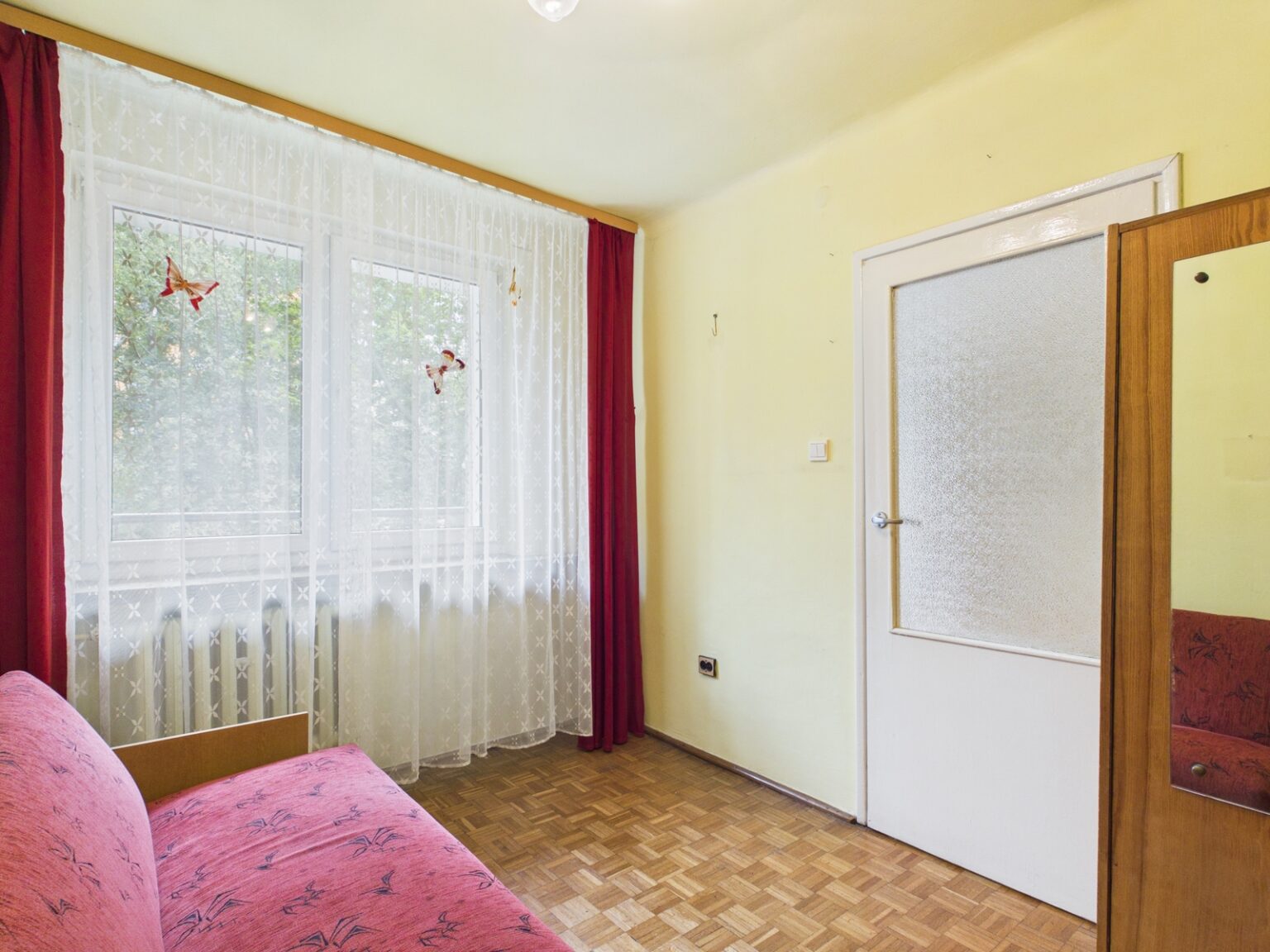 Jasny pokój z różową sofą i dużym oknem