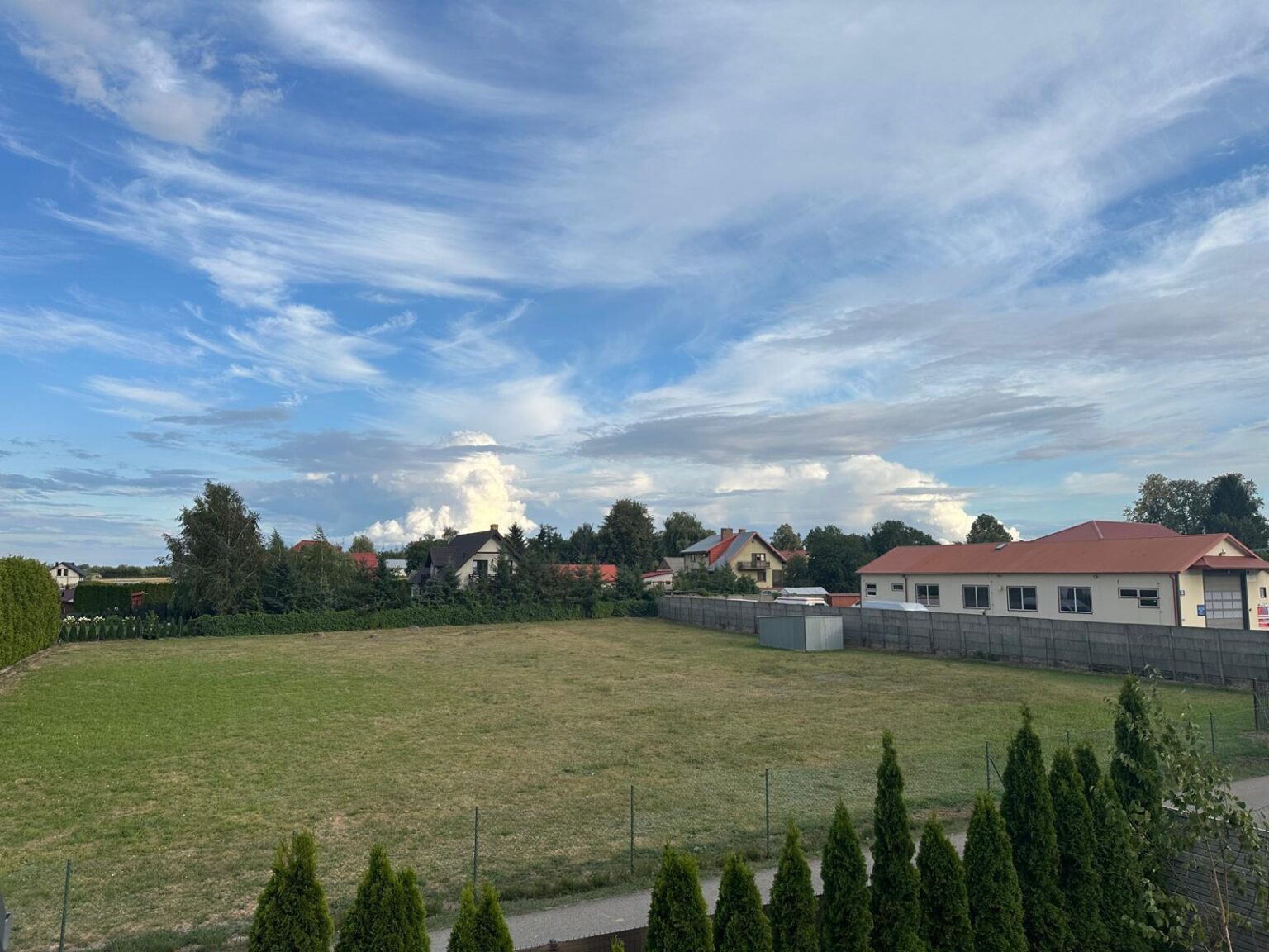 Osiedle domów z rozległym niebem i pierzastymi chmurami