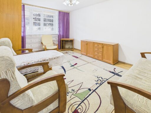 Jasny salon z fotelami, kanapą i drewnianą komodą