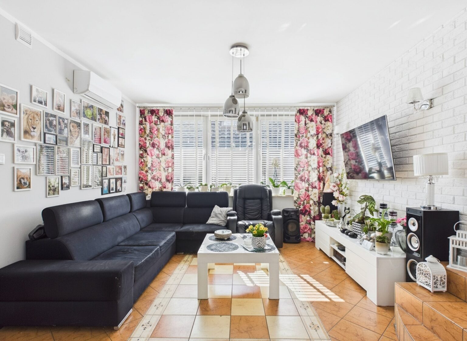 Jasny salon z czarną sofą i kwiatowymi zasłonami