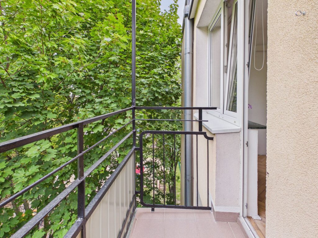Wąski balkon z widokiem na zielone drzewa